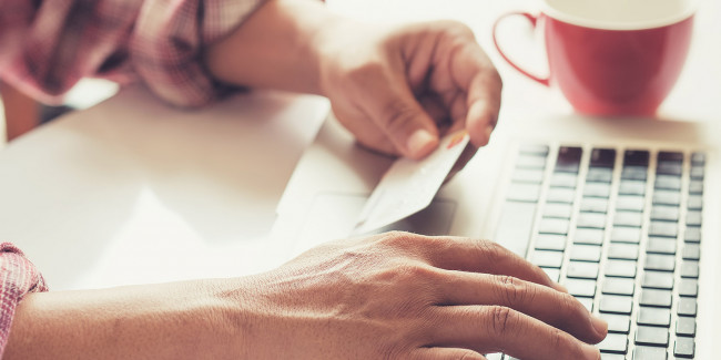 Man's hands holding a credit card and using pc or laptop for online shoppin