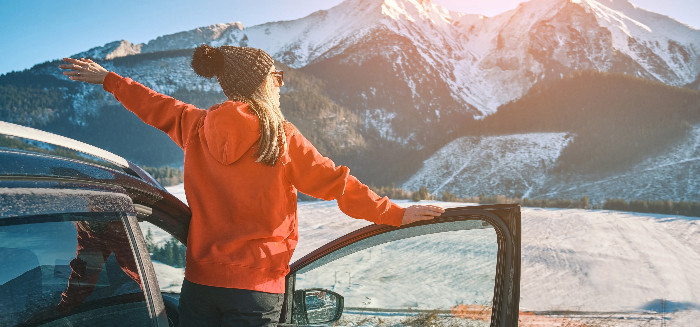 Woman standing outside her car near mountain