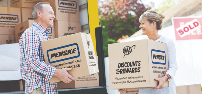 Couple holding moving boxes outside sold house 
