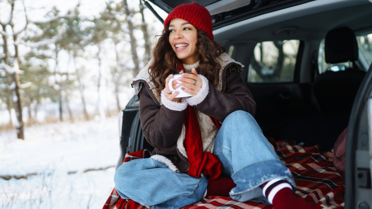 girl sitting in back of car enjoying hot drink