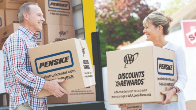 Couple holding moving boxes outside sold house 