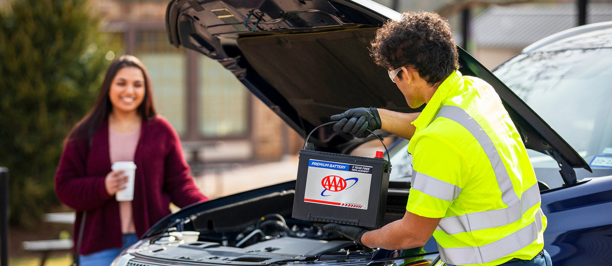 AAA technician bringing a car battery to customer