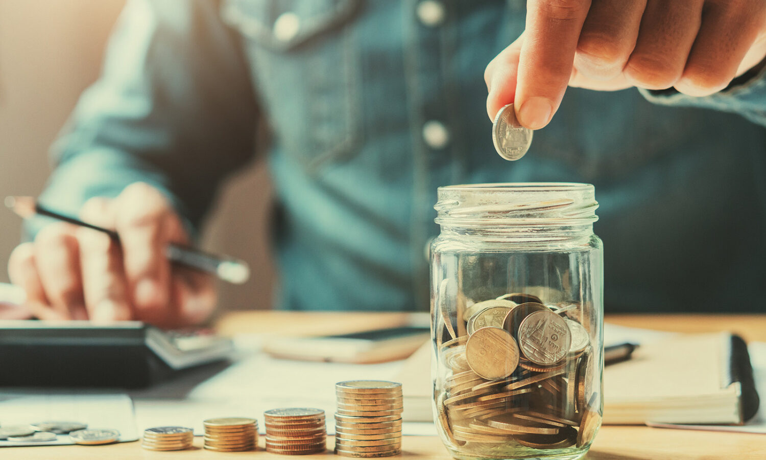 person putting coins in a jar